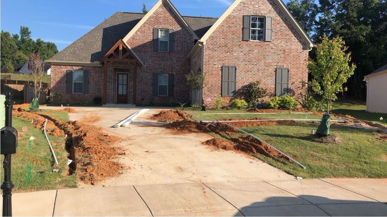 New irrigation system installation in progress at a new-build home in Oxford, MS, trench cut along the driveway by Oxford Lawn Pro